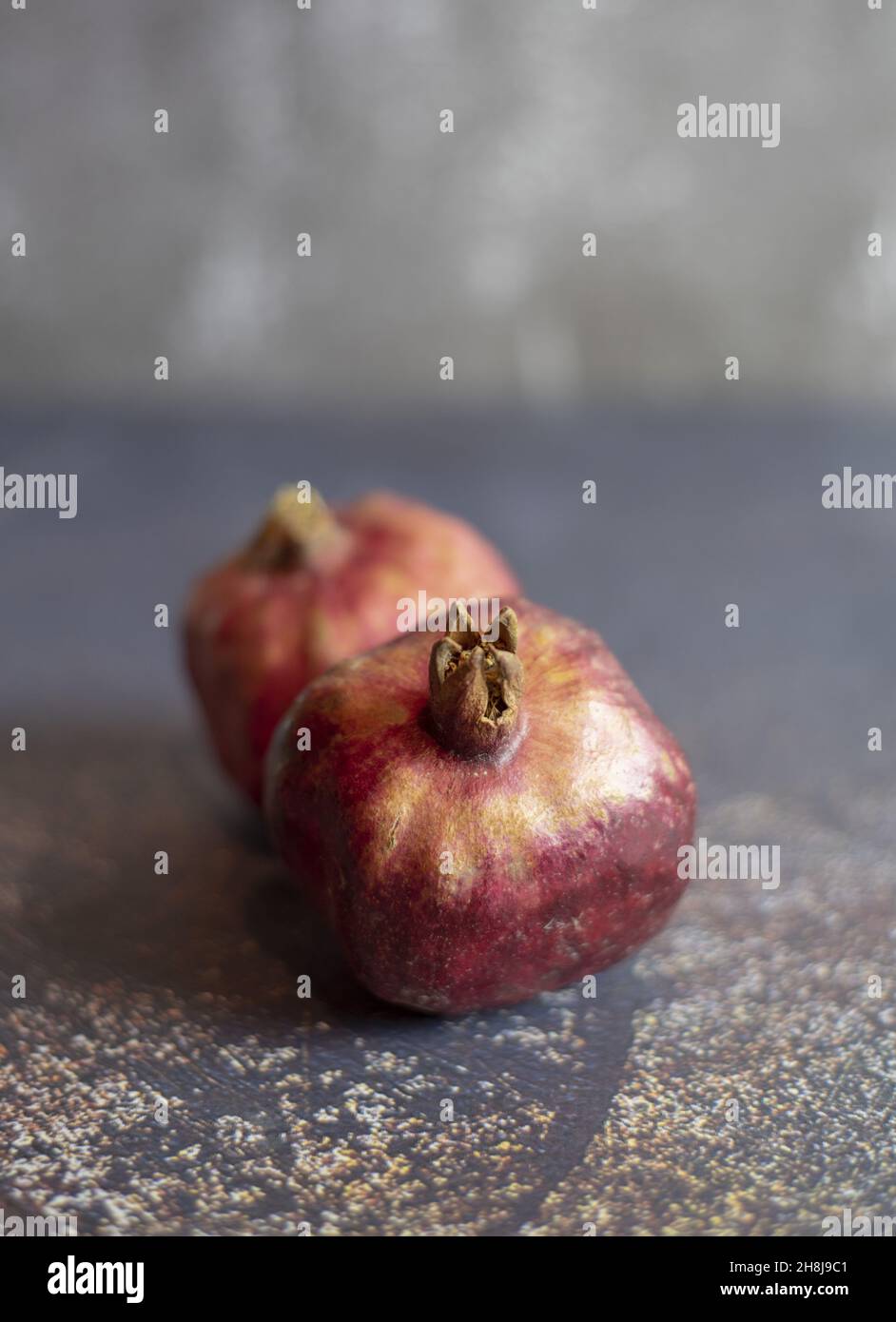 Due melagrane succose mature su un piano di cemento. Sfondo alimentare. Foto Stock