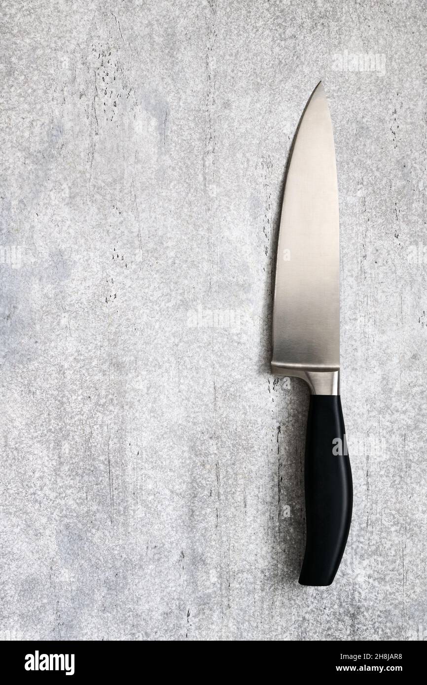 Grande coltello professionale da cucina su sfondo grigio in cemento con uno spazio per il testo, vista dall'alto Foto Stock