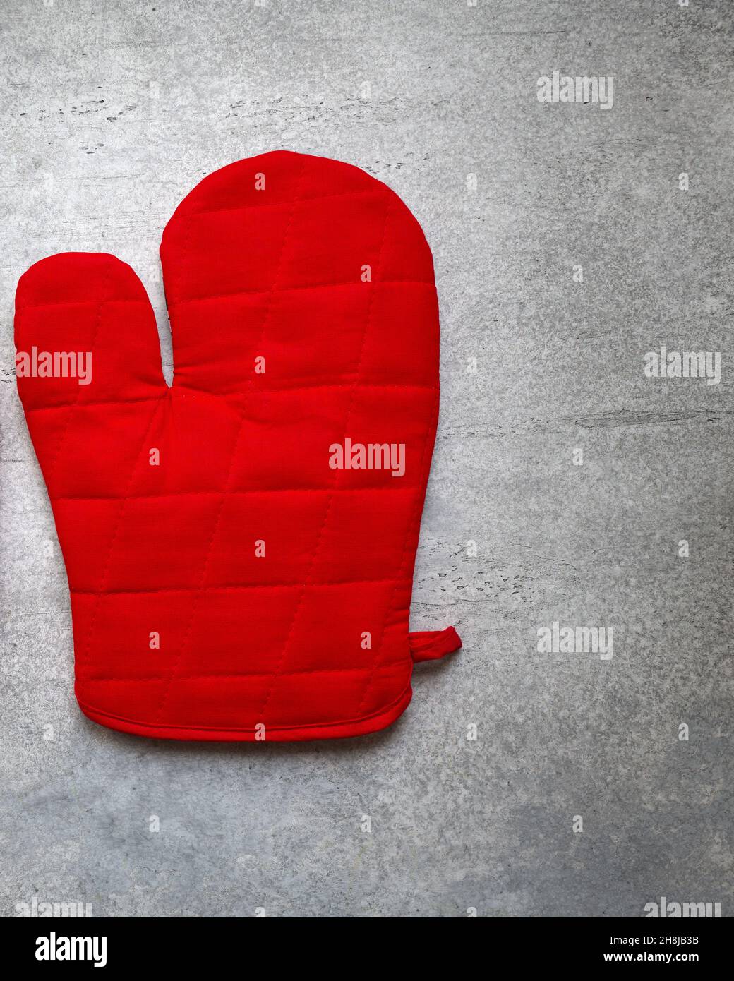 Guanto rosso per vassoi e padelle, fondo in cemento grigio, primo piano Foto Stock