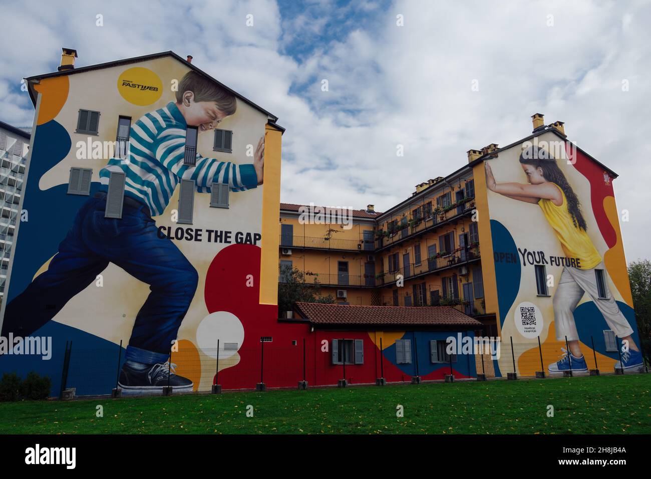 Milano, Italia colorati graffiti da parete. Murale di Street art dell'artista Rosk raffigurante i bambini che spingono un muro con il messaggio chiudere il Gap, aprire il vostro futuro. Foto Stock