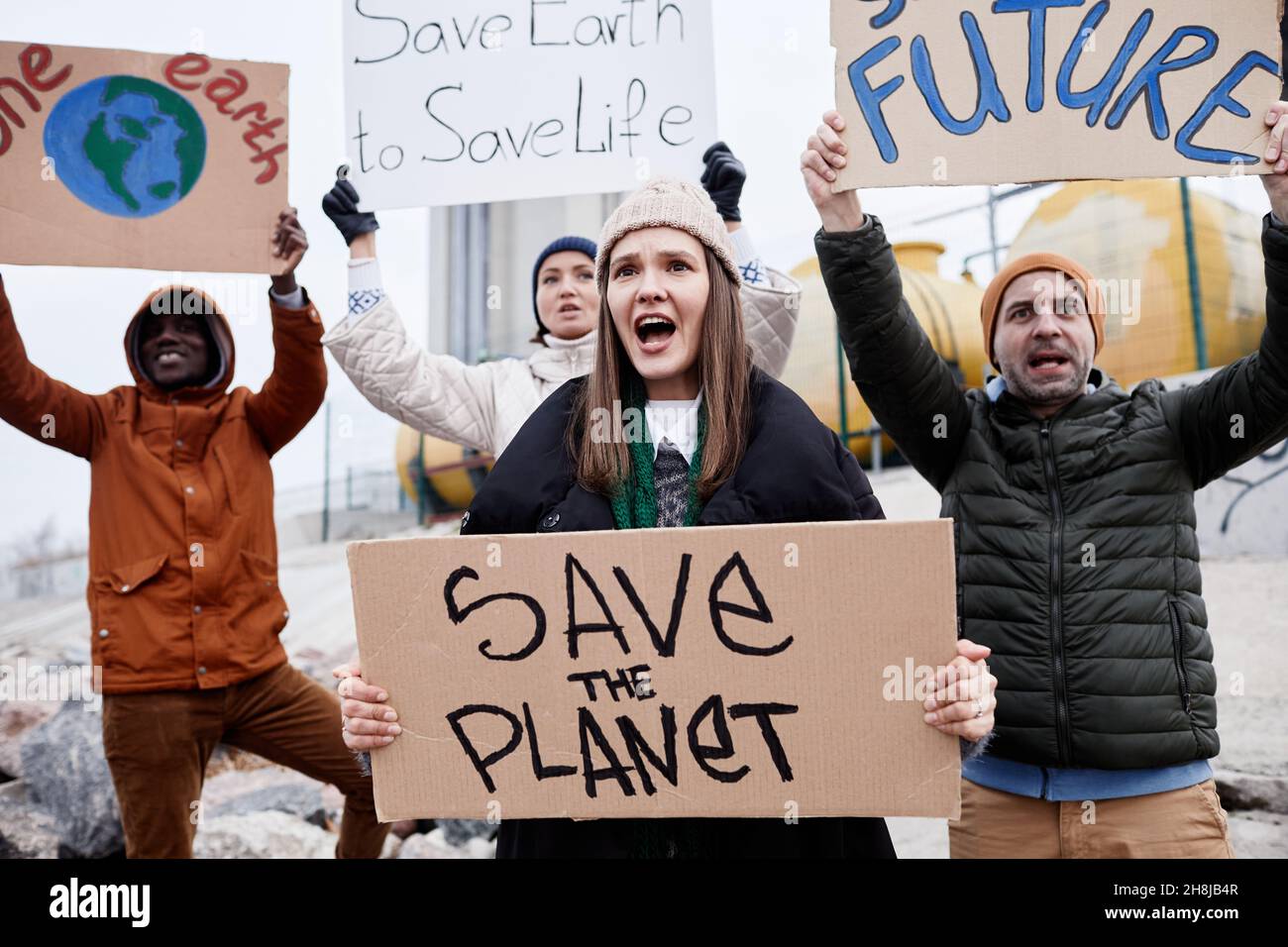 Ritratto di giovane donna che porta segni e grida protestando nel sito di disastro ambientale Foto Stock