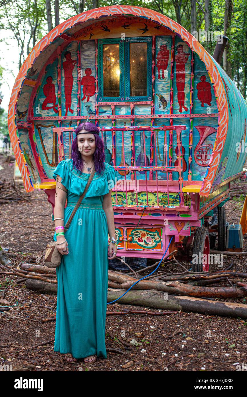Giovane ragazza bohémien hippie in piedi di fronte alla tradizionale zingara caravan o carrello in foresta. Foto Stock
