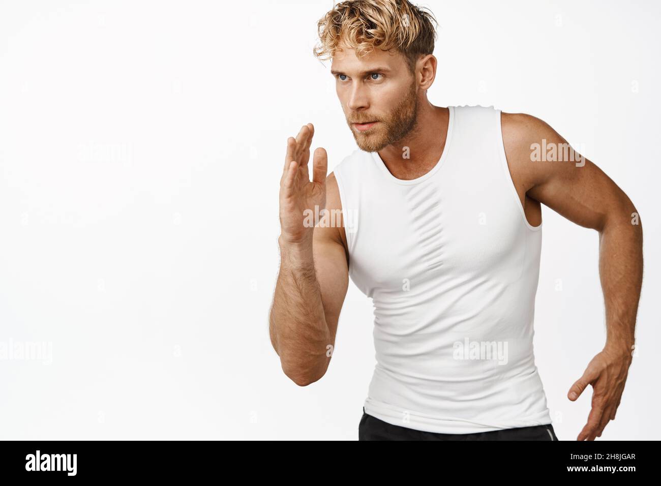 Immagine di un bel pareggiatore che corre, fa allenarsi e guarda determinato, in piedi su sfondo bianco Foto Stock