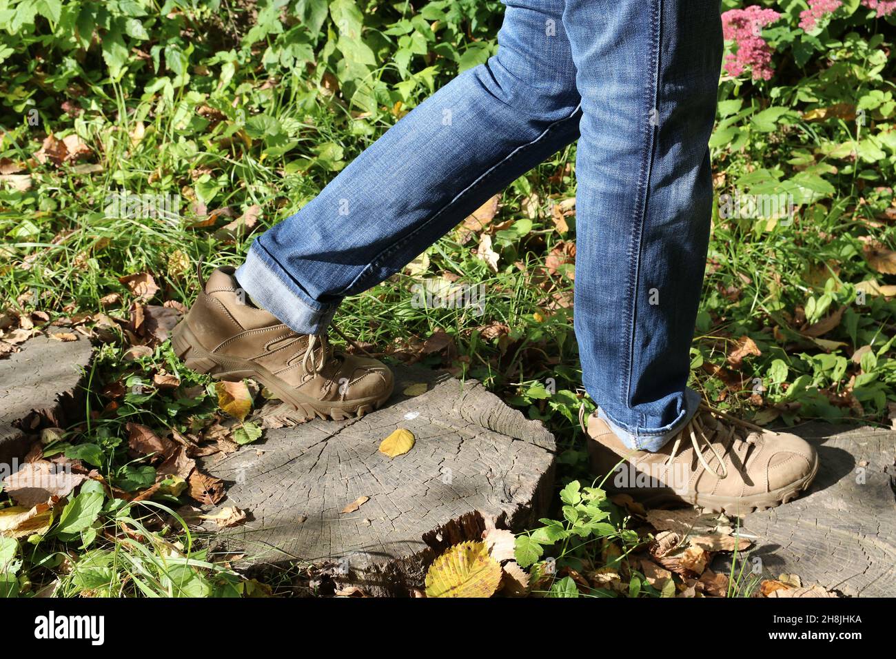 Un uomo cammina lungo un sentiero forestale. Gambe in pantaloni e stivali. Foto Stock