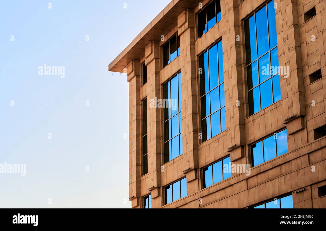 Vista di una moderna casa d'affari con facciata in ceramica rivestita e grandi finestre in vetro solido pannello. Edificio al dettaglio con esterni in piastrelle di sabbia contro il cielo blu Foto Stock