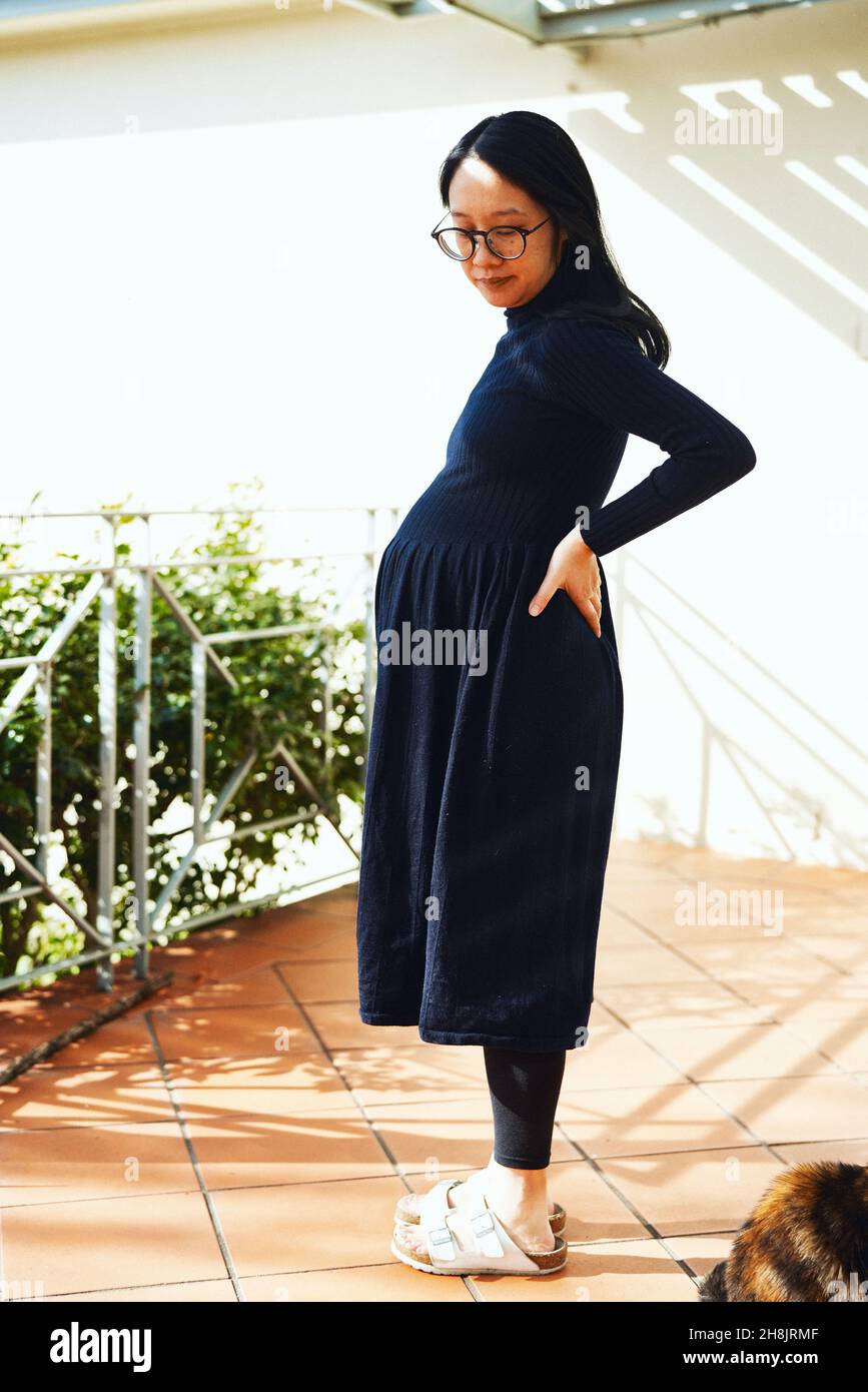 Donna incinta sul portico al sole Foto Stock