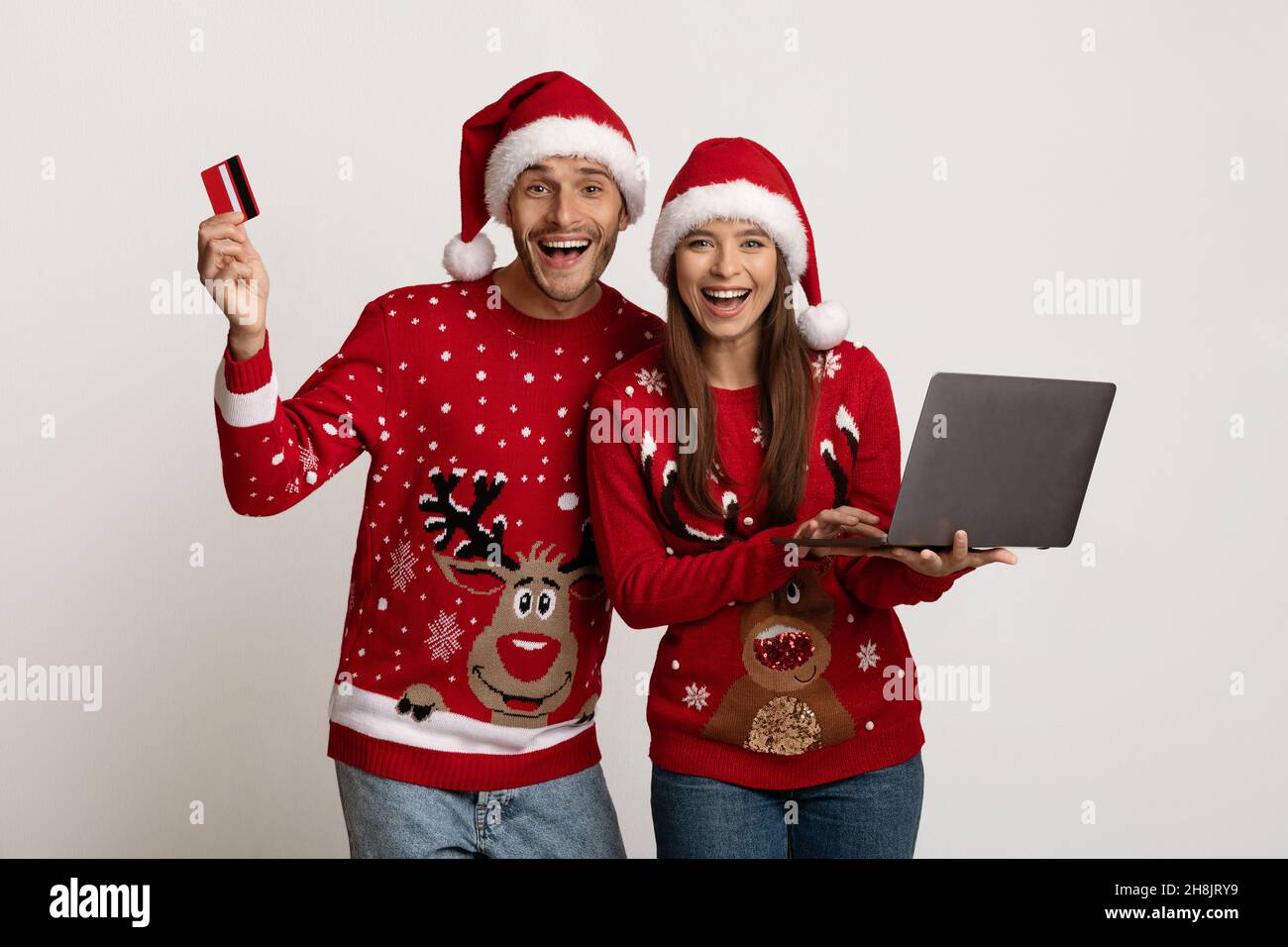 Acquista regali online. Coppia che indossa il laptop e la carta di credito Santa Capps Holding Foto Stock