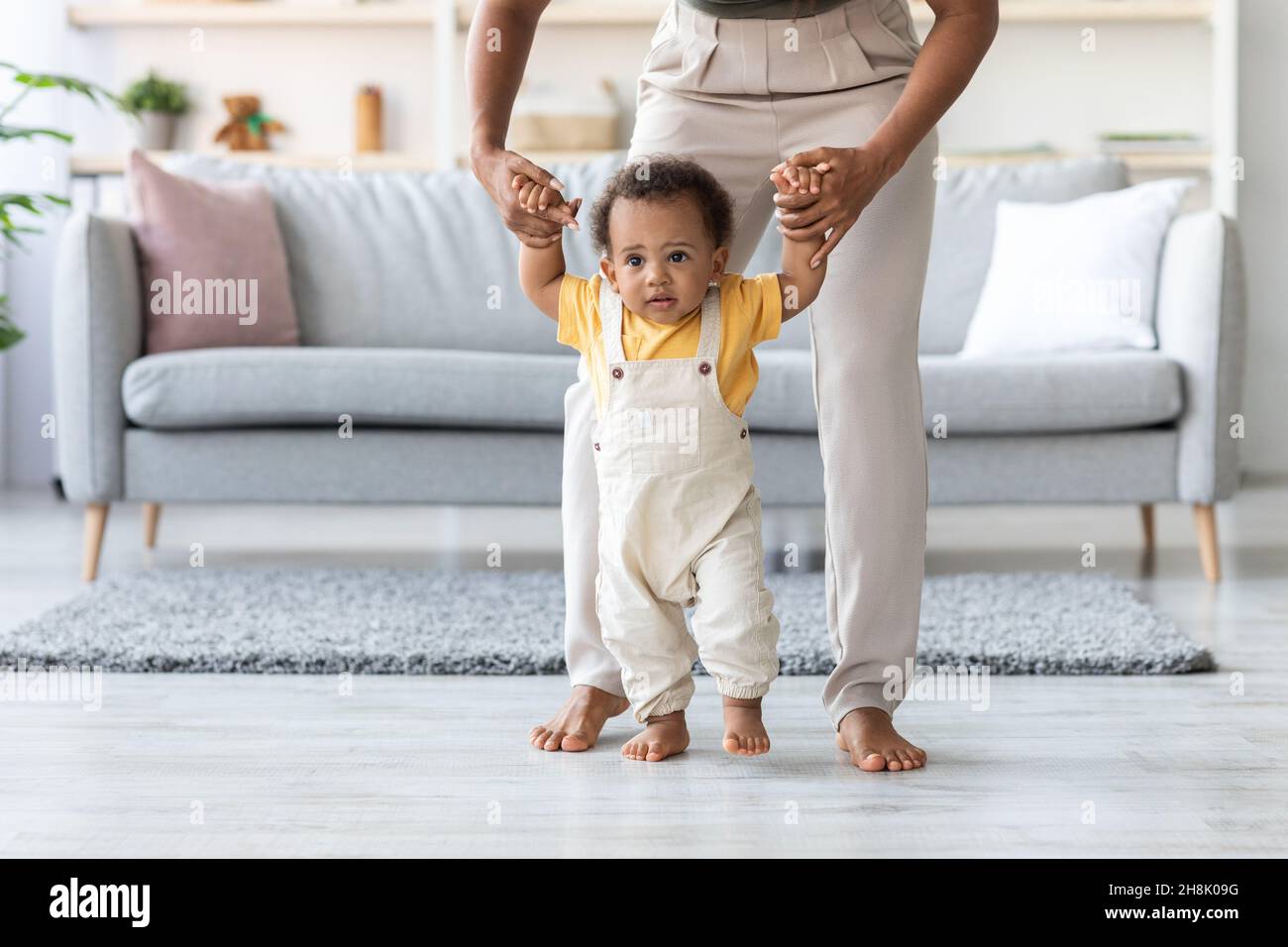 Il bambino ameriano africano carino che fa i primi punti con l'aiuto della madre Foto Stock