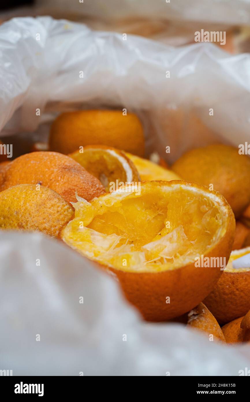 Primo piano delle bucce d'arancia rimanenti in un sacchetto di plastica. Arance vecchie e usate gettate via dopo sono state usate per fare il succo fresco dell'arancia. Foto Stock