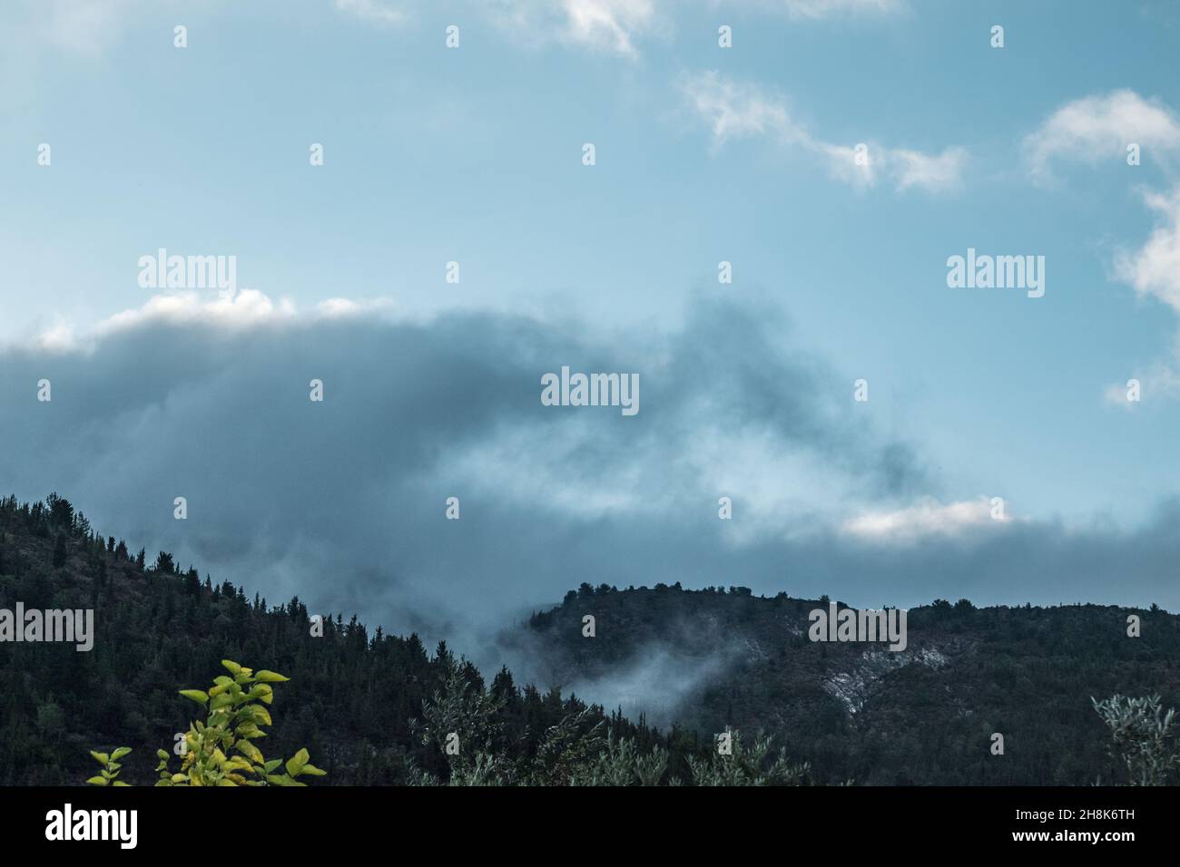 Paesaggio nuvoloso mistico sulle verdi colline greche. Nuvole basse su cielo panoramico sopra le colline verde scuro sull'isola di Lefkada, Grecia Foto Stock