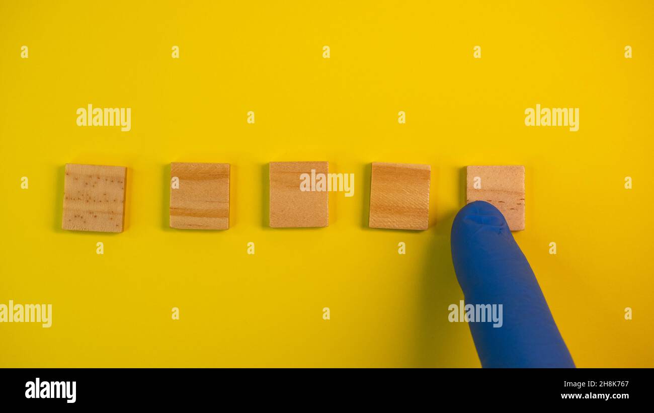 I guanti blu puntano su blocchi di legno puliti su sfondo giallo colorato. Tema medico scientifico o biologico. Modello per testo o concetto. R Foto Stock
