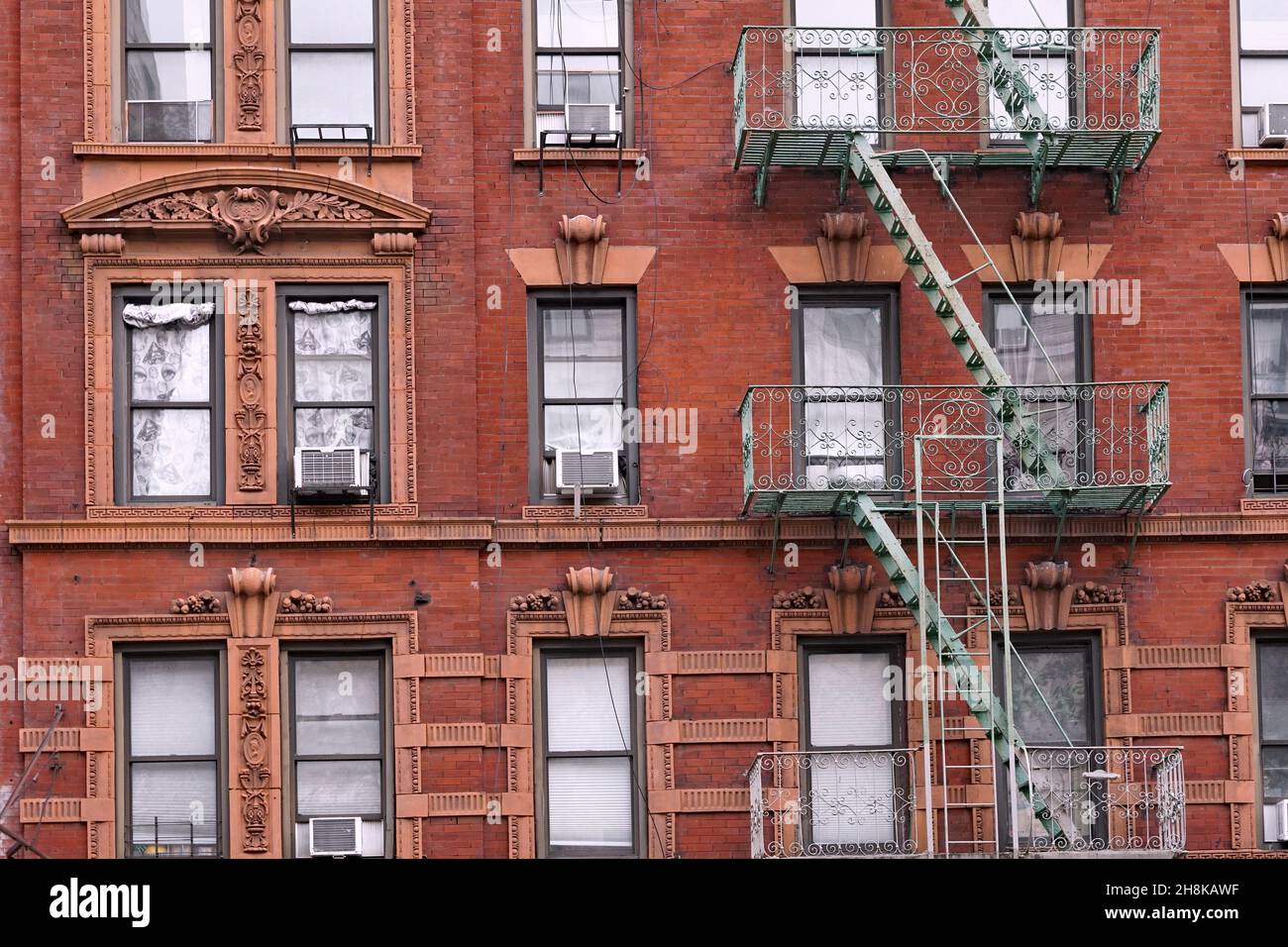 Vecchio edificio di appartamenti di New York con fantasia terracotta dettagli intorno alle finestre e scala esterna fuoco Foto Stock