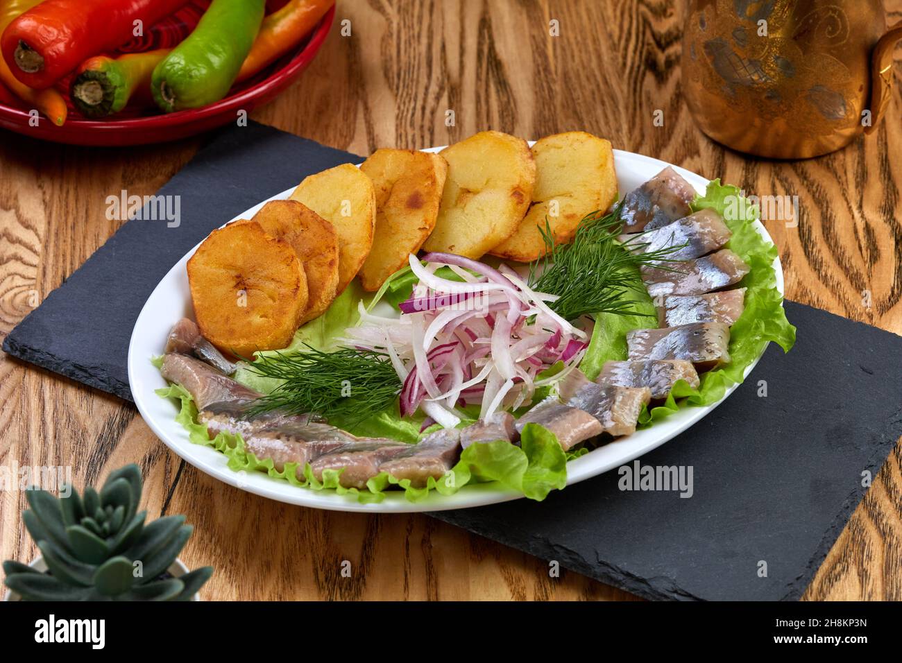 aringa marinata con patate al forno e cipolle in piastra di terracotta Foto Stock
