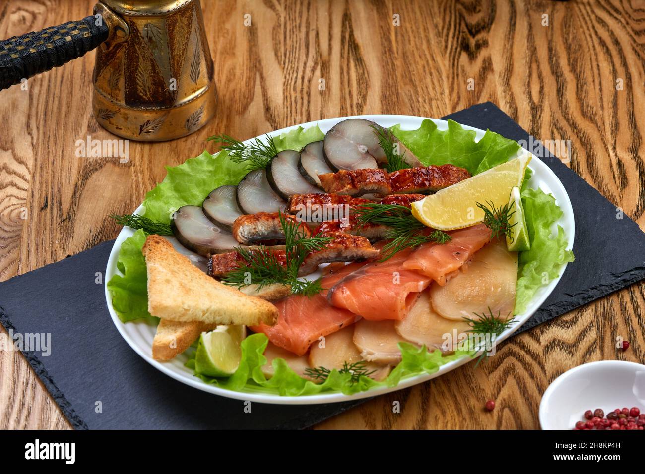 Piatto di pesce con diversi tipi di pesce affumicato e salato, con limone, insalata e crostini Foto Stock