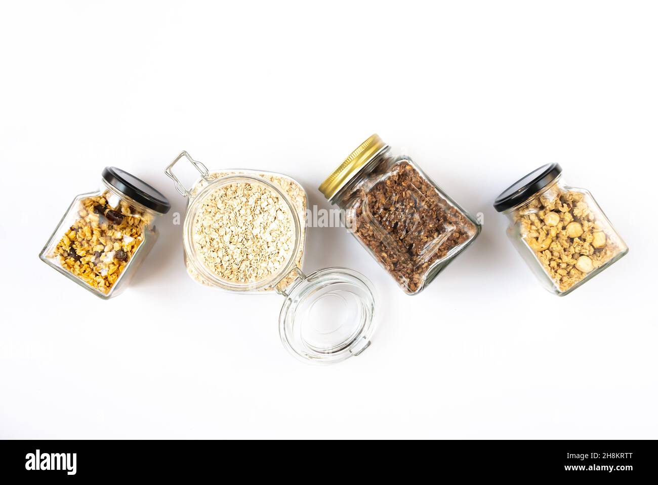 Vista dall'alto di vasetti pieni di avena e vari granoli croccanti - frutta secca, noci e cioccolato. Concetto di mangiare sano. Foto Stock