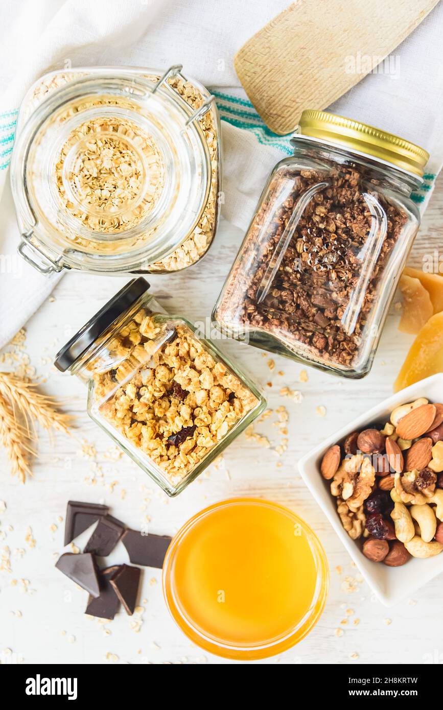 Vista dall'alto di vasetti pieni di avena e vari granoli croccanti - frutta secca, noci e cioccolato. Concetto di mangiare sano. Foto Stock
