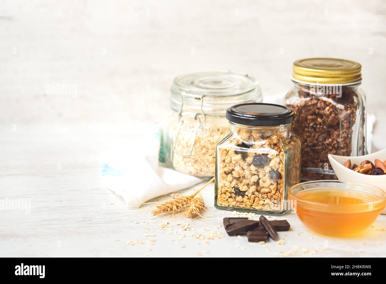 Vasetti pieni di avena e vari granoli croccanti - frutta secca, frutta secca, noci e cioccolato. Concetto di mangiare sano. Spazio di copia. Foto Stock