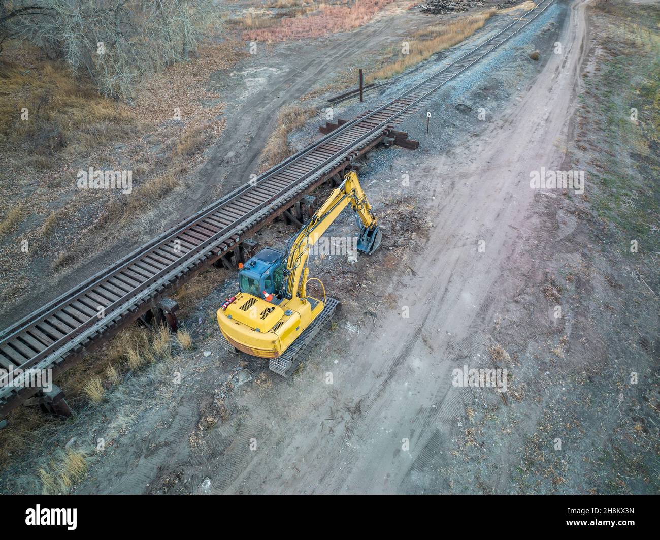 escavatore retroescavatore, binario e cavalletto ferroviario - vista aerea in autunno, Foto Stock