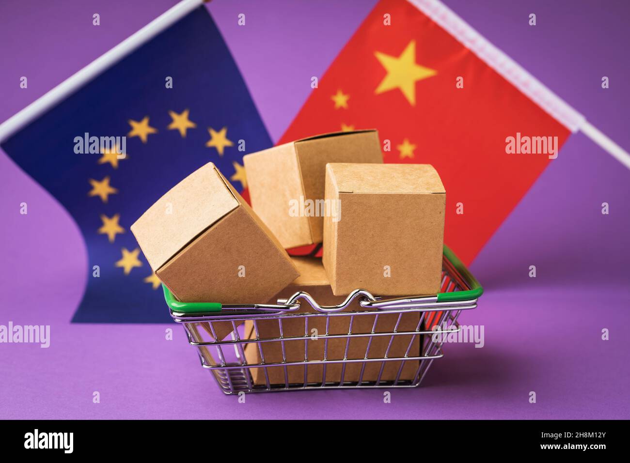 Scatole di cartone in un cestino alimentare, bandiere della Cina e dell'Unione europea su uno sfondo colorato, il concetto di commercio tra paesi Foto Stock