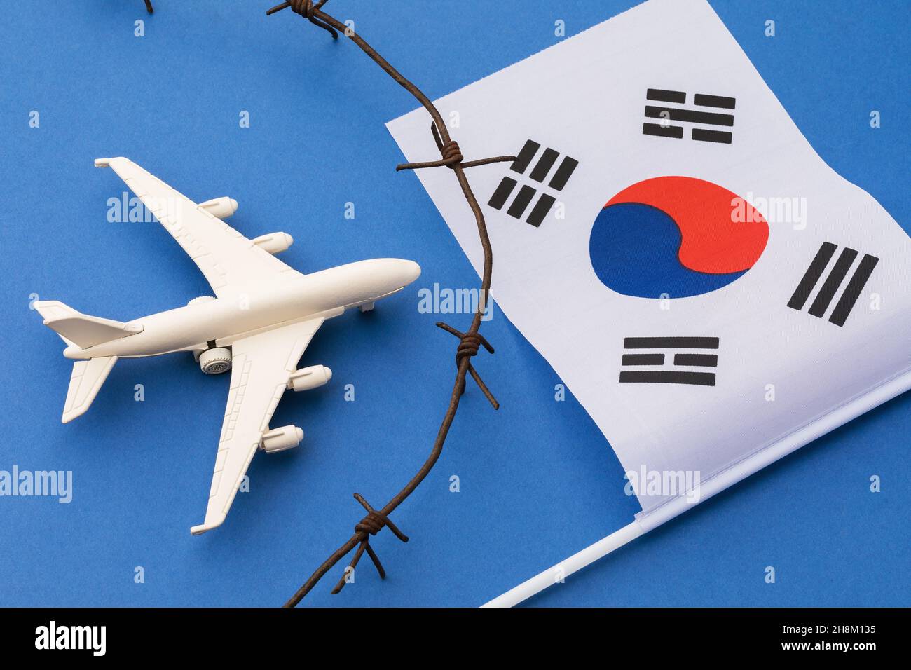 Aereo giocattolo, bandiera della Corea del Sud e filo spinato su sfondo colorato, concetto di violazione del confine aereo della Corea del Sud Foto Stock
