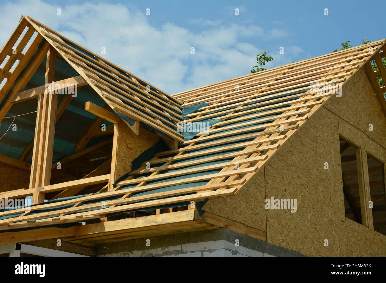 Costruzione di tetti con finestre sottotetto sul palco di costruzione di tetti in legno con barriera al vapore, membrana impermeabile installata. Foto Stock