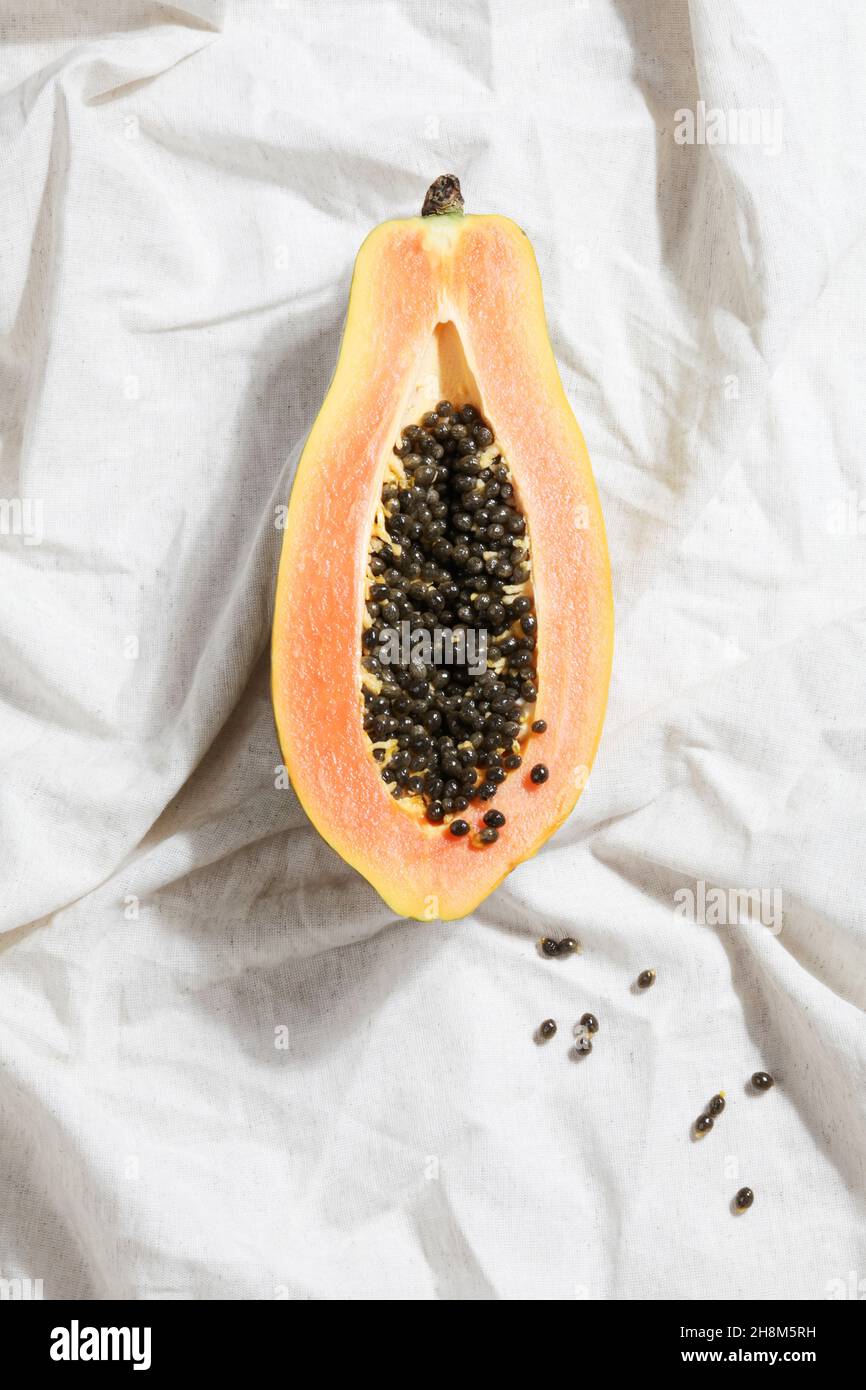 concetto di cibo creativo con metà papaya su bisso grigio. Vista dall'alto piatta. Sfondo naturale minimalista e colorato. Foto Stock