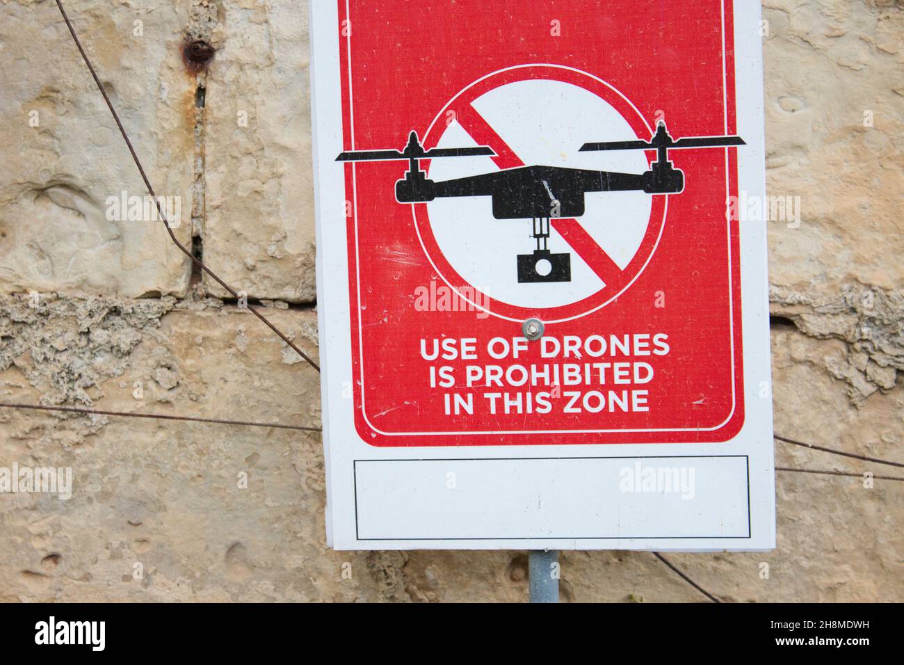 Un segno rosso che recita 'l'uso di droni è vietato in questa zona' contro un muro di mattoni Foto Stock