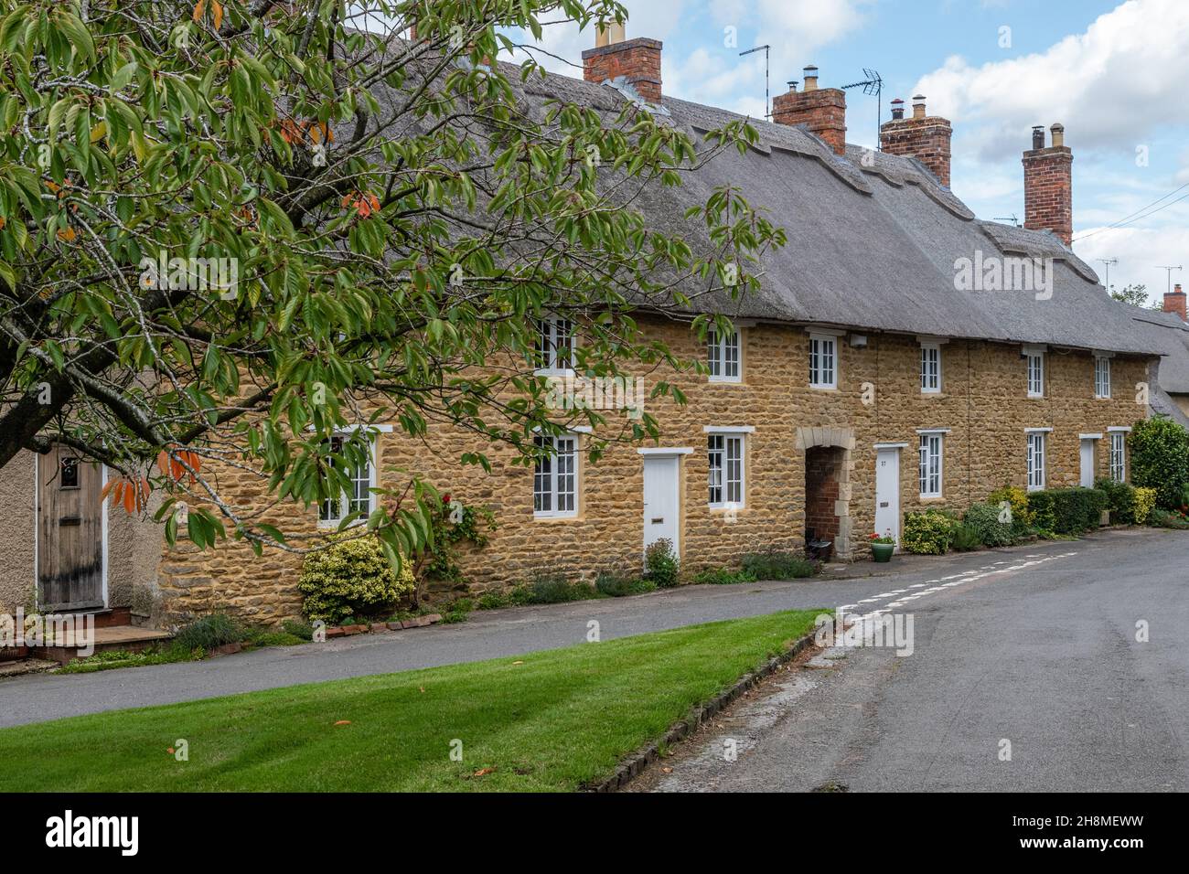 Terrazza di graziose case in pietra costruita con tetto in paglia nel villaggio di Ashby St Ledgers, Northamptonshire, Regno Unito Foto Stock
