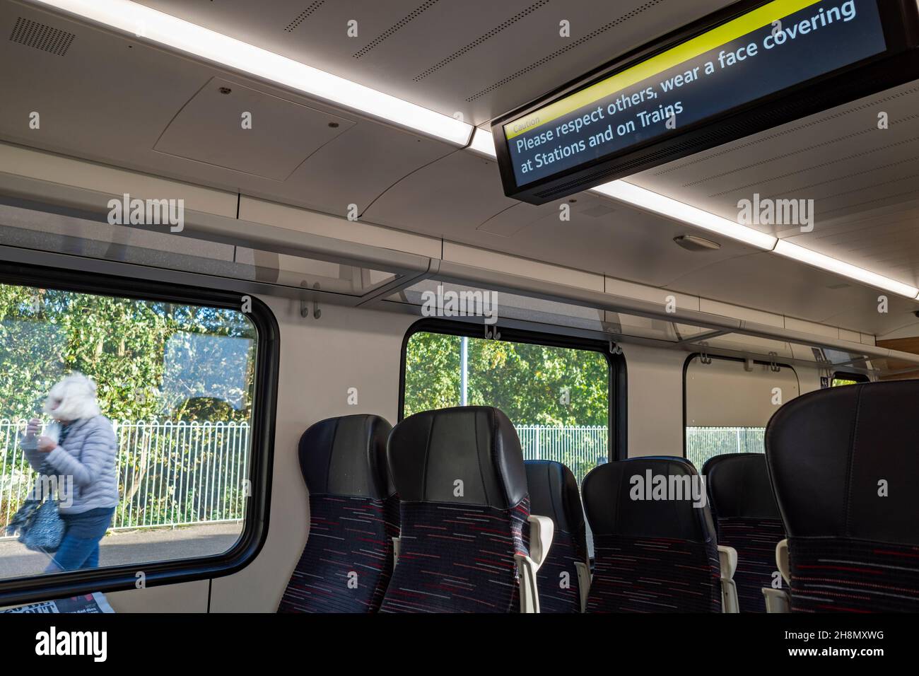 Informazioni sul treno a bordo che consigliano ai passeggeri di indossare una copertura per il viso Foto Stock