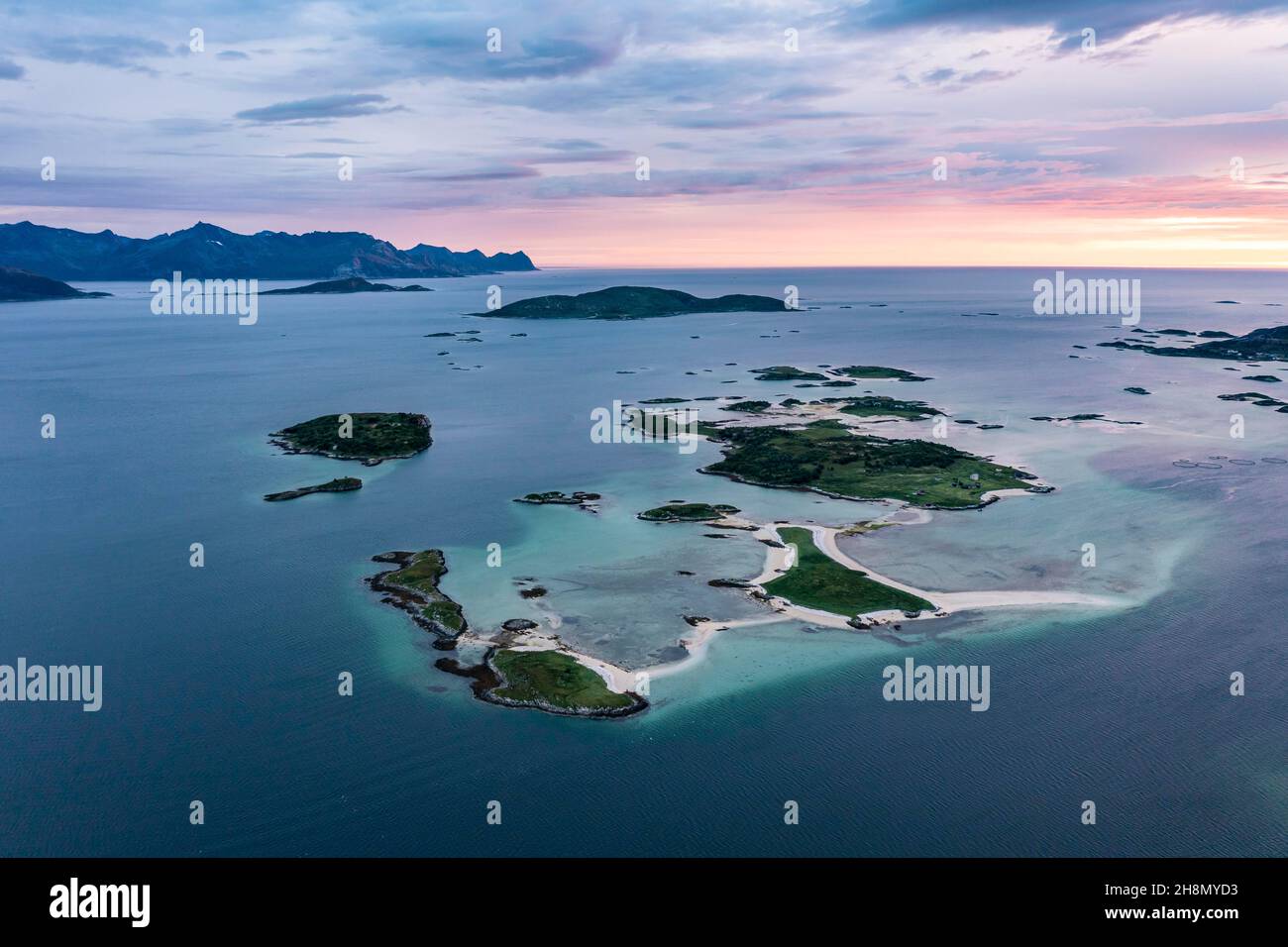 Vista delle piccole isole nel mare vicino Sommaroy, montagne dell'isola di Senja sul retro, vista aerea al tramonto, Kvaloya, Troms og Finnmark, Norvegia Foto Stock