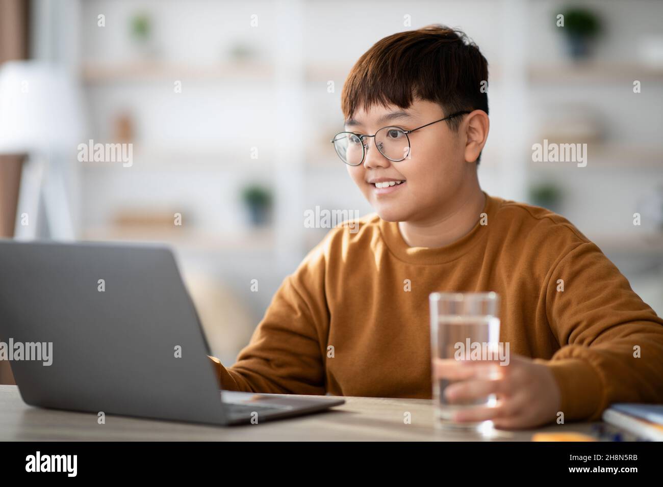 Bambino asiatico sano bere acqua mentre fare i compiti Foto Stock