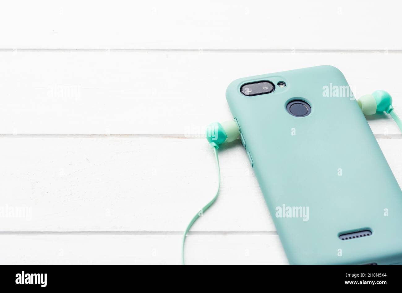 Telefono digitale con protezione e cuffie al tavolo, primo piano con spazio per il pattern Foto Stock