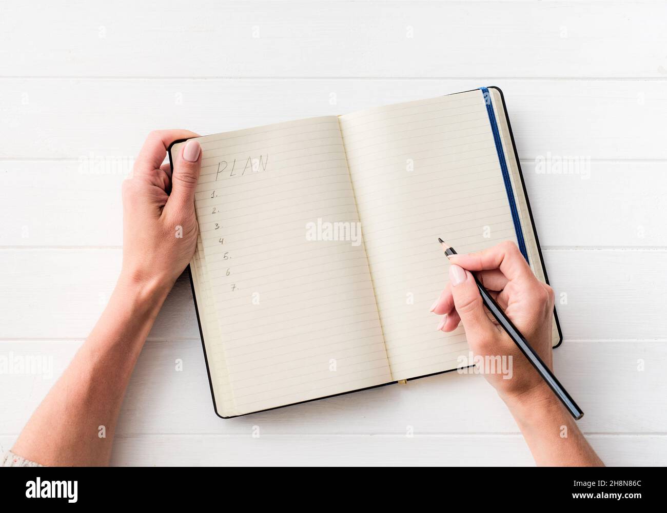 Vista dall'alto della ragazza che crea un piano in un notebook Foto Stock
