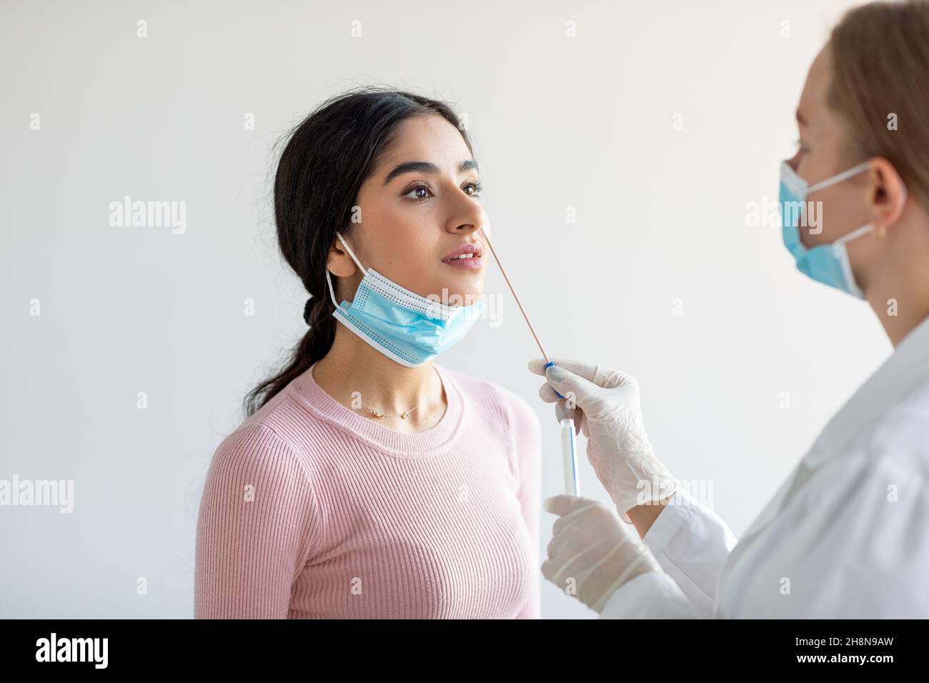 Giovane donna indiana che assume il test COVID-19 con procedura diagnostica con sonda tampone nasale Foto Stock