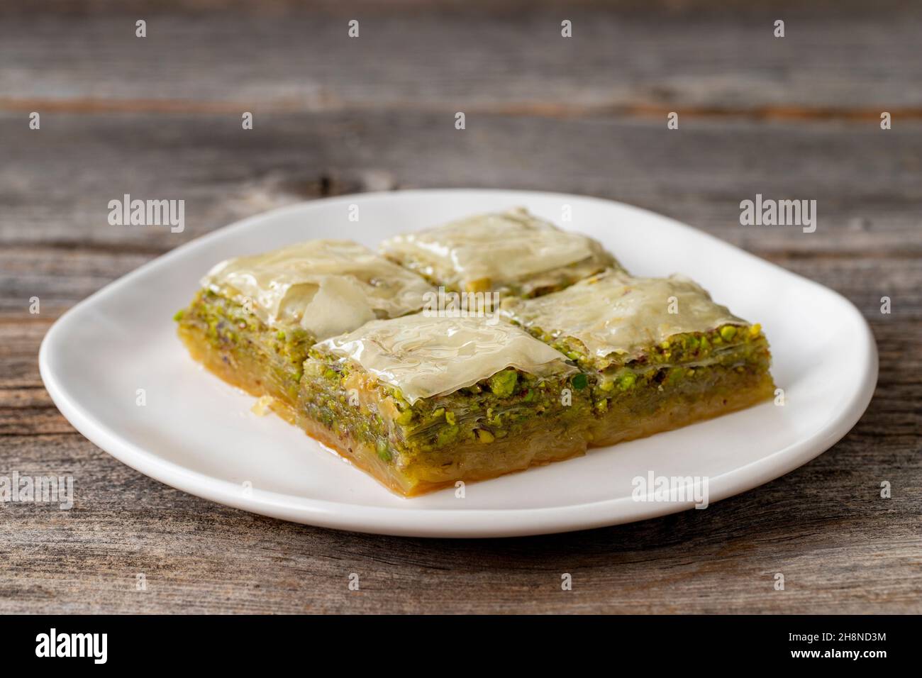 Pistacchio baklava su sfondo ligneo. Presentazione e servizio di pistacchio baklava in stile turco. Vista orizzontale. Primo piano Foto Stock