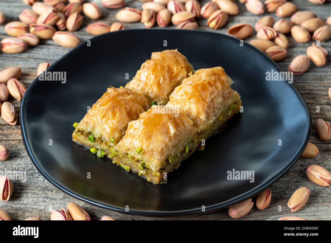 Pistacchio baklava su sfondo ligneo. Presentazione e servizio di pistacchio baklava in stile turco. Vista orizzontale. Primo piano Foto Stock