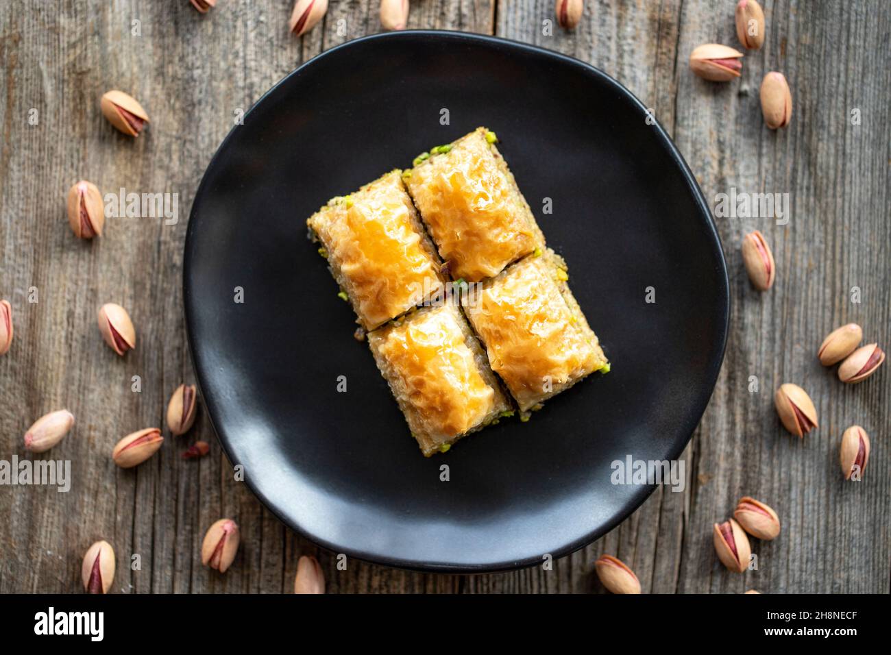 Pistacchio baklava su sfondo ligneo. Presentazione e servizio di pistacchio baklava in stile turco. Vista dall'alto. Primo piano Foto Stock