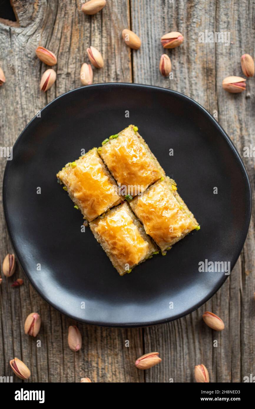 Pistacchio baklava su sfondo ligneo. Presentazione e servizio di pistacchio baklava in stile turco. Vista dall'alto. Primo piano Foto Stock