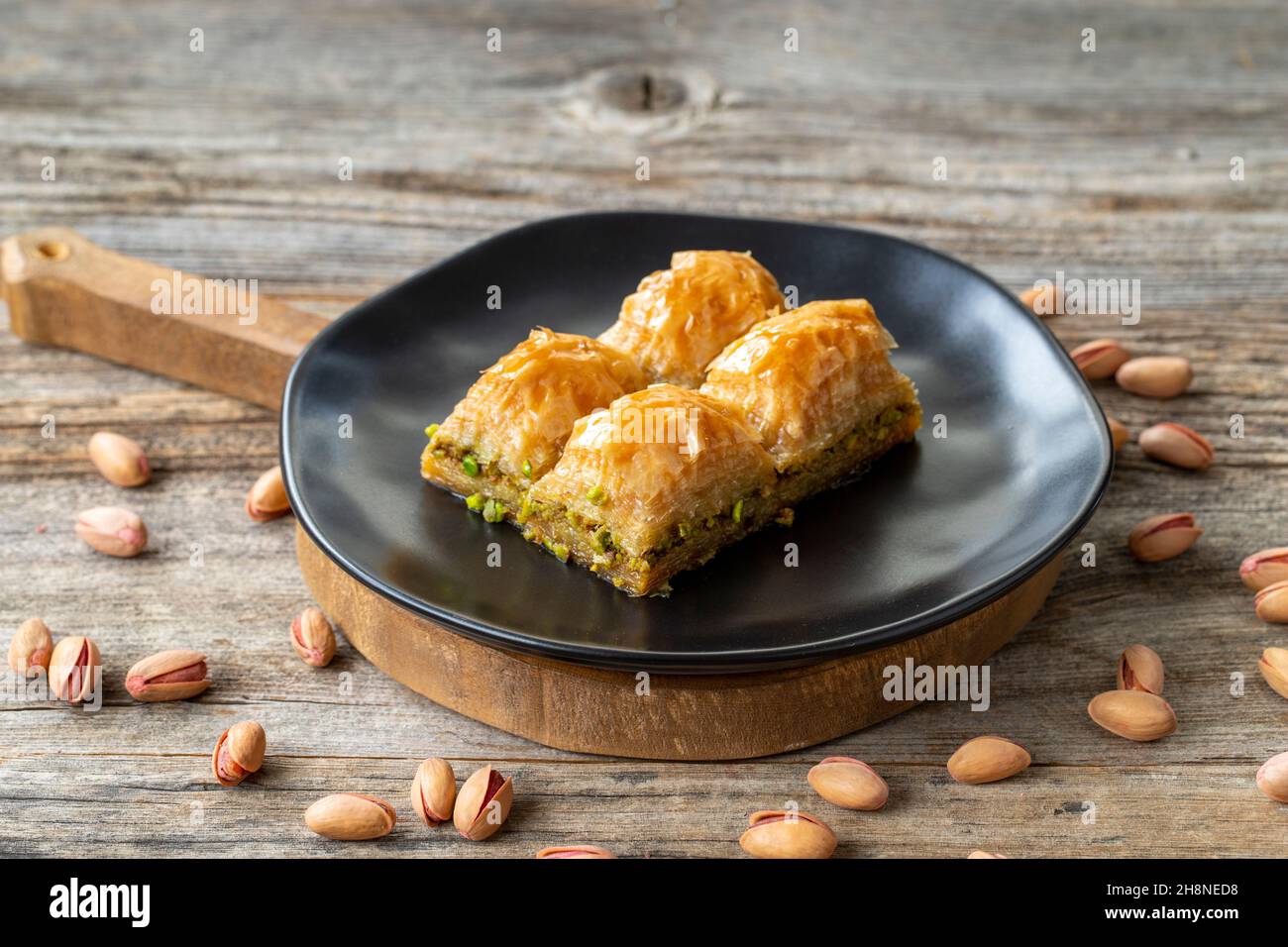 Pistacchio baklava su sfondo ligneo. Presentazione e servizio di pistacchio baklava in stile turco. Vista orizzontale. Primo piano Foto Stock