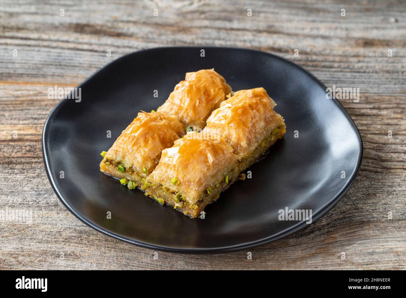 Pistacchio baklava su sfondo ligneo. Presentazione e servizio di pistacchio baklava in stile turco. Vista orizzontale. Primo piano Foto Stock