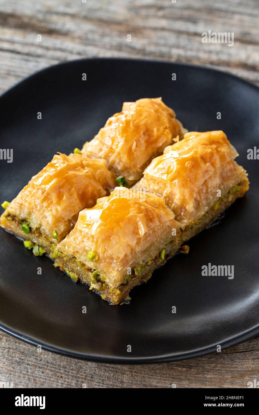 Pistacchio baklava su sfondo ligneo. Presentazione e servizio di pistacchio baklava in stile turco. Vista verticale. Primo piano Foto Stock