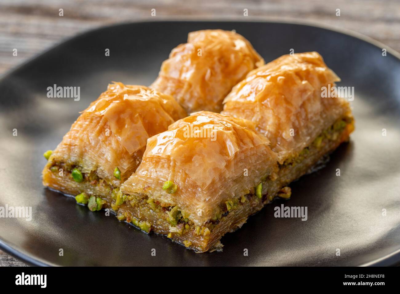 Pistacchio baklava su sfondo ligneo. Presentazione e servizio di pistacchio baklava in stile turco. Vista orizzontale. Primo piano Foto Stock
