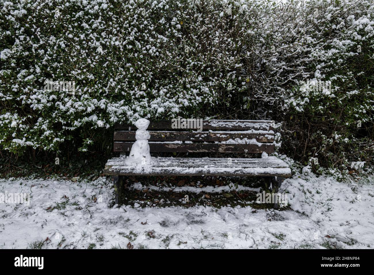 Un mini snowman su una panca parco, Brungerley Park, Clitheroe, Ribble Valley, Lancashire, REGNO UNITO. Foto Stock