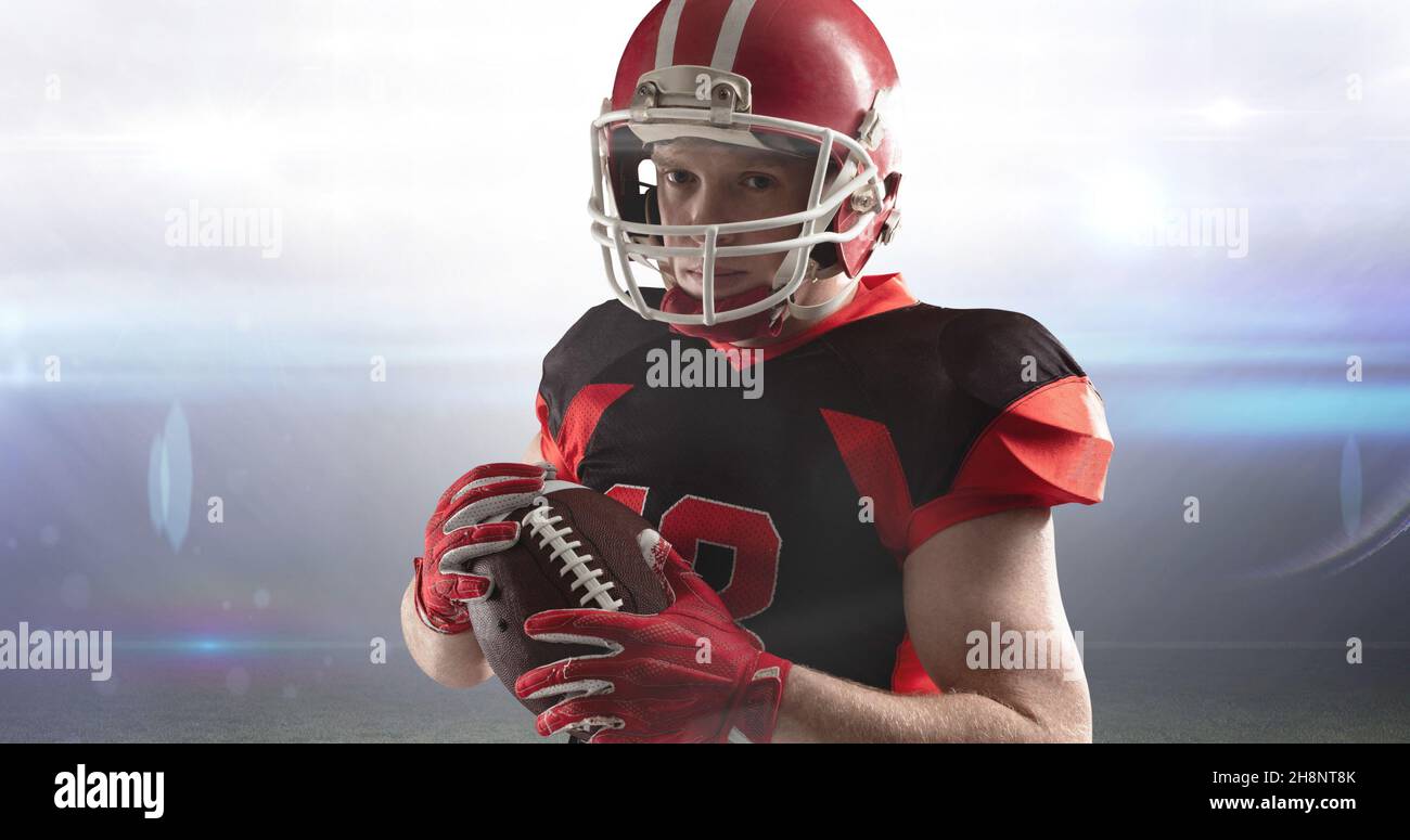 Ritratto di atleta fidato maschile in abbigliamento da calcio americano che tiene la palla allo stadio Foto Stock