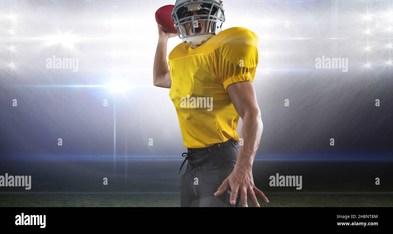 Atleta di calcio americano maschile che sta per lanciare la palla allo stadio illuminato Foto Stock