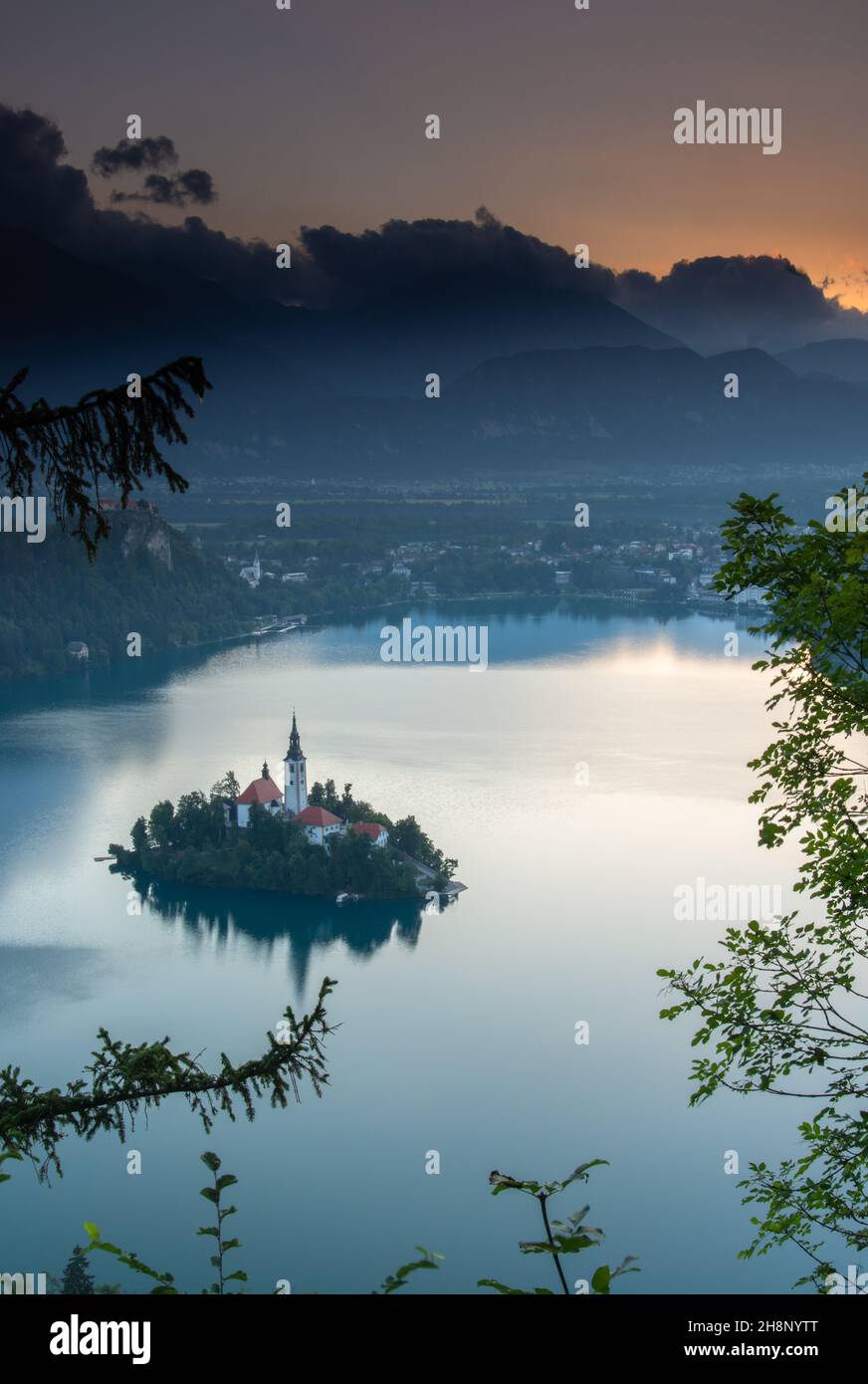 Piccola isola con Chiesa cattolica nel lago di Bled, Slovenia all'alba con il castello e le montagne sullo sfondo. Nell'estate 2020. Foto Stock