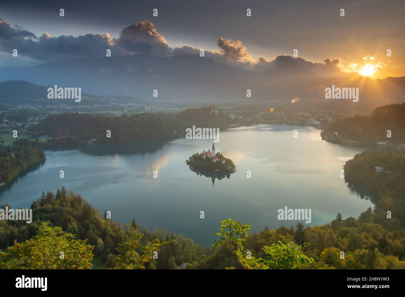 Piccola isola con Chiesa cattolica nel lago di Bled, Slovenia all'alba con il castello e le montagne sullo sfondo. Nell'estate 2020. Foto Stock