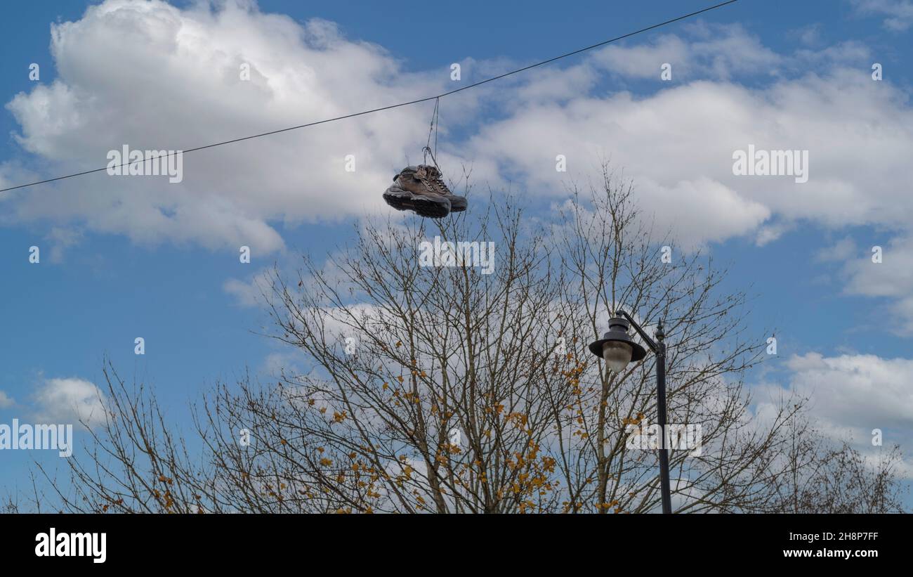 Coppia di scarpe marroni da passeggio appese su un filo dai loro lacci Foto Stock