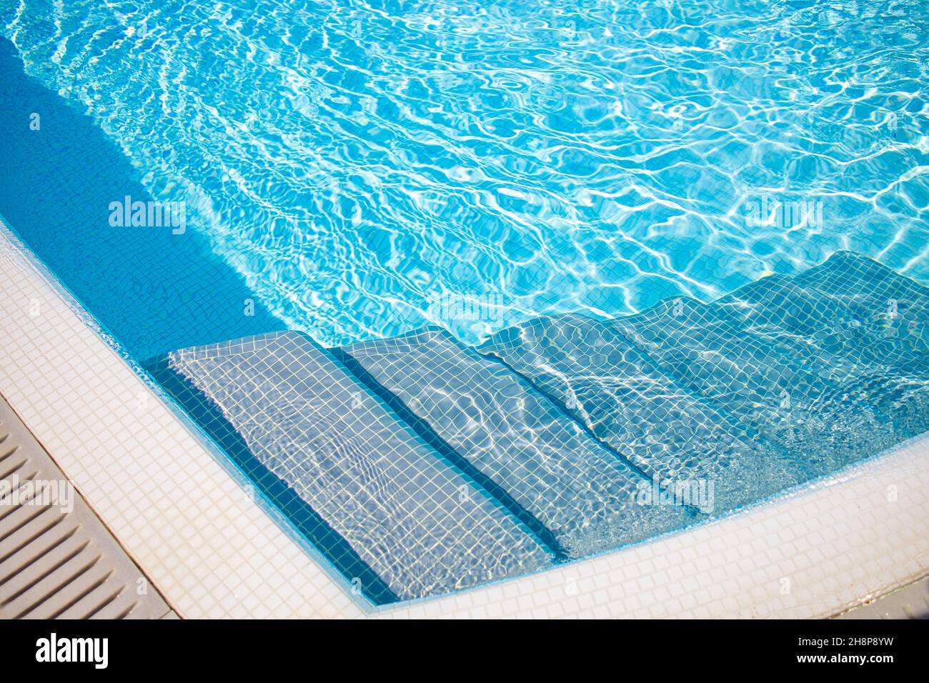 Bordo della piscina blu. Sport d'acqua d'estate, sfondo ricreativo. Consistenza della superficie dell'acqua, blu turchese brillante luminoso luminoso scale di primo piano soleggiato Foto Stock