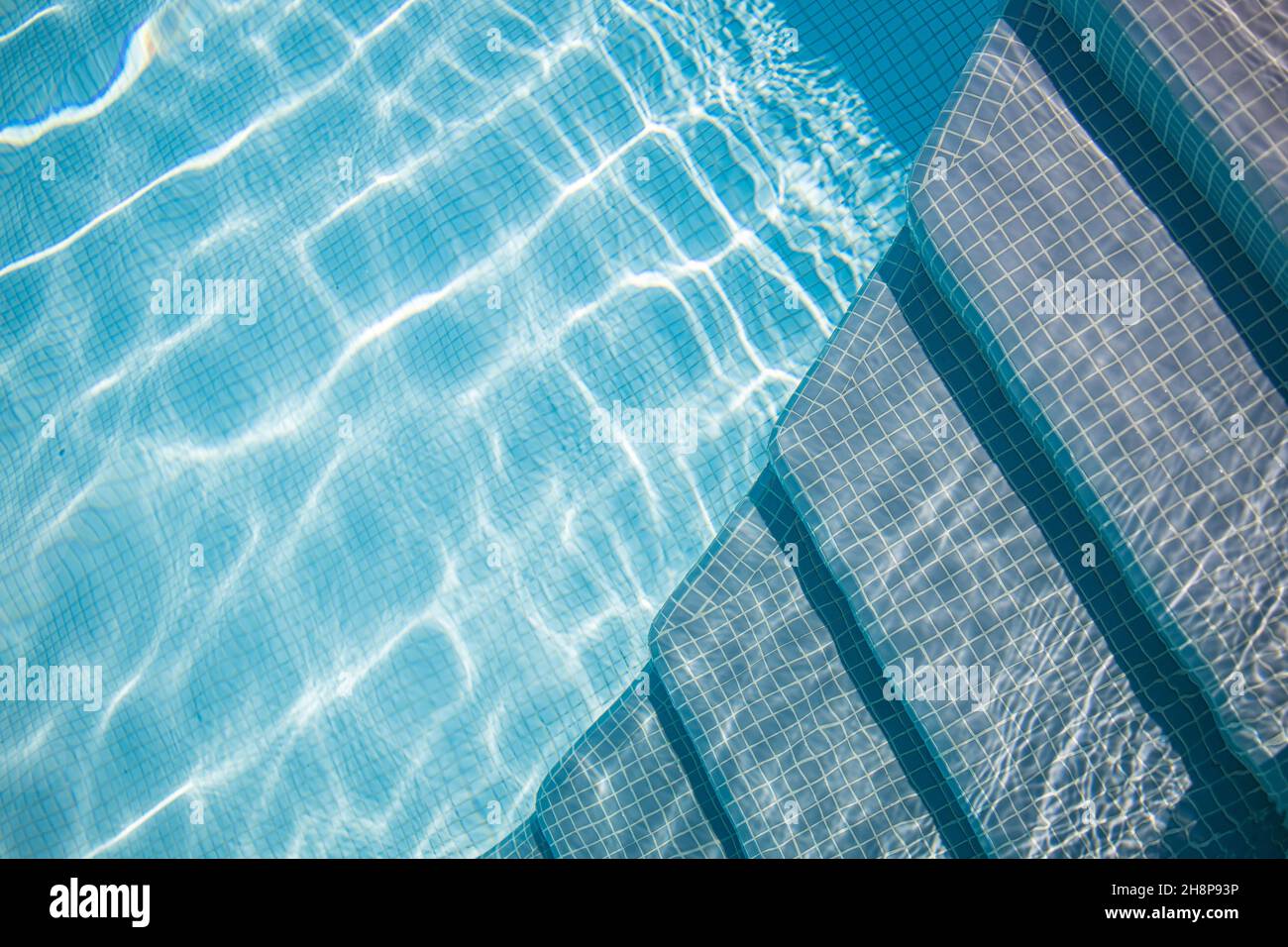 Bordo della piscina blu. Sport d'acqua d'estate, sfondo ricreativo. Consistenza della superficie dell'acqua, blu turchese brillante luminoso luminoso scale di primo piano soleggiato Foto Stock